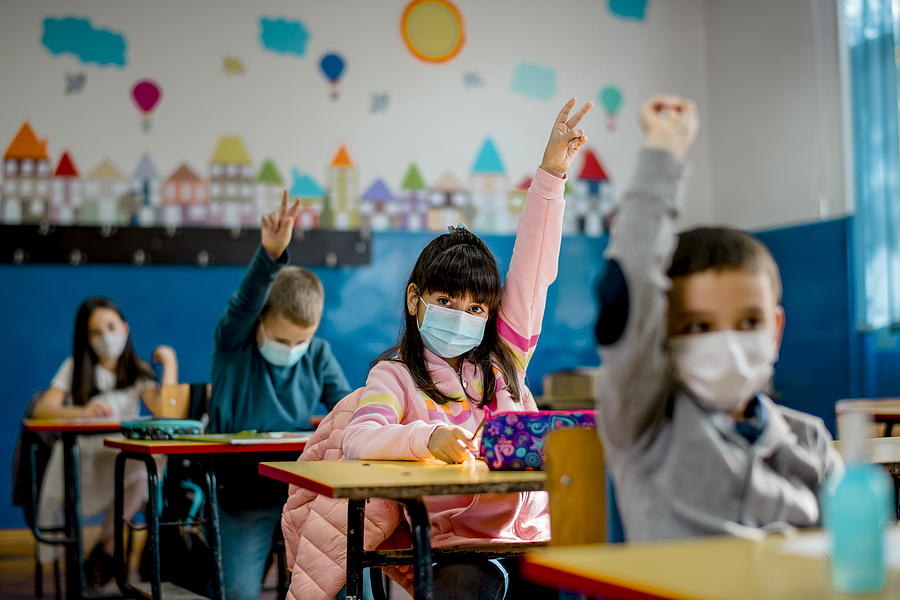 Elementary schoolchildren wearing a protective face masks  in the classroom. Education during epidemic. Photograph by Kevajefimija