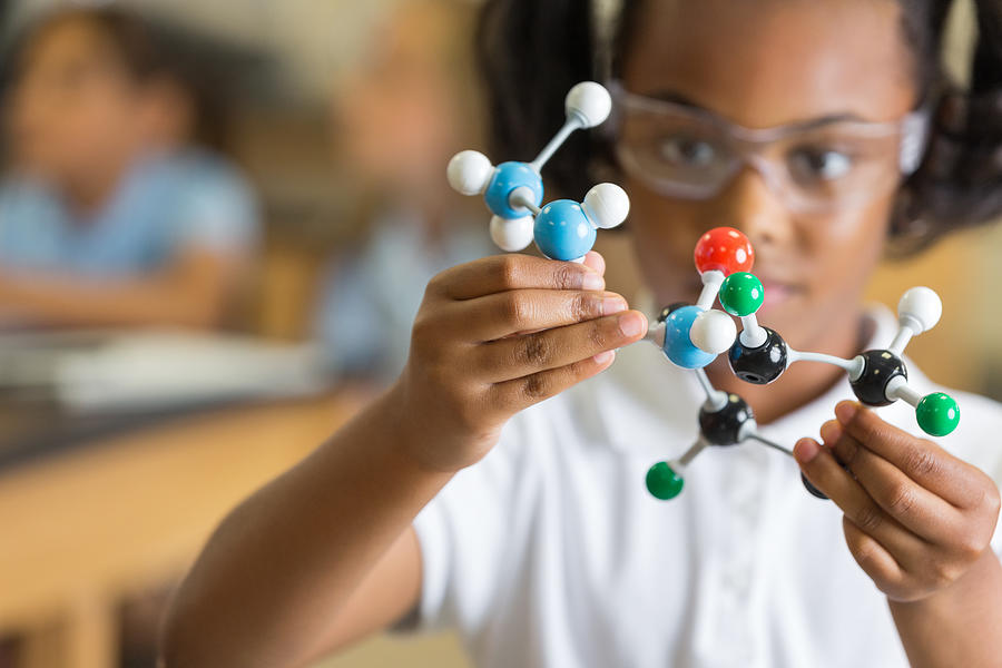 Elementary science student using plastic atom model educational toy Photograph by SDI Productions
