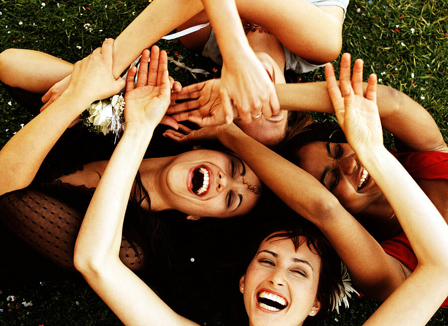 Elevated view of a group of young women lying on a lawn with their hands together Photograph by Stockbyte