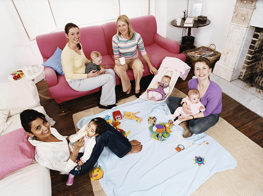 Elevated View of Mothers Playing with Babies in a Living Room Photograph by Digital Vision.