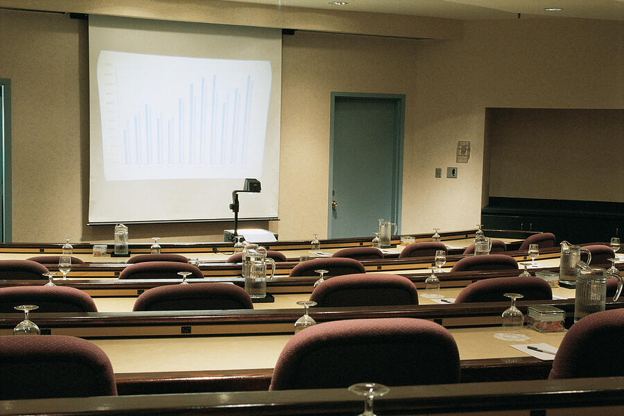 Empty seminar room with screen and overhead projector Photograph by Comstock