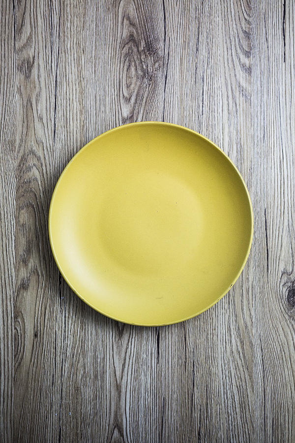 Empty yellow plate on wood Photograph by Westend61