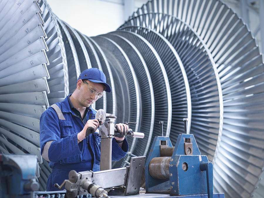 Engineer at workstation in front of steam turbine Photograph by Monty Rakusen
