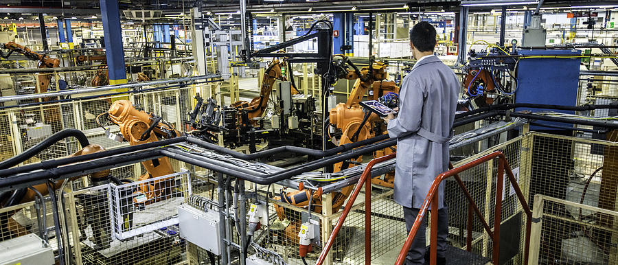 Engineer overseeing automated production process in a factory Photograph by Vm