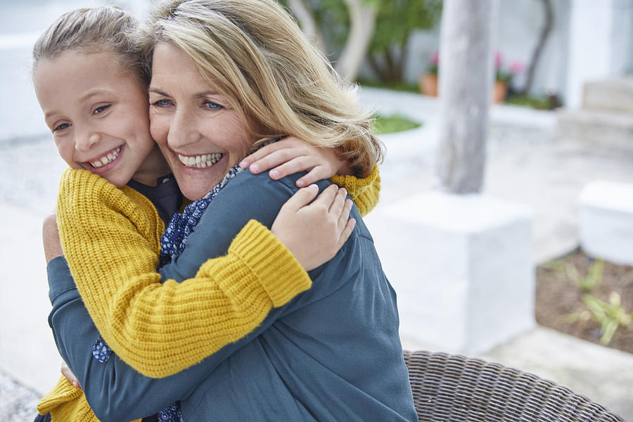 Enthusiastic grandmother and granddaughter hugging on patio Photograph by Caia Image