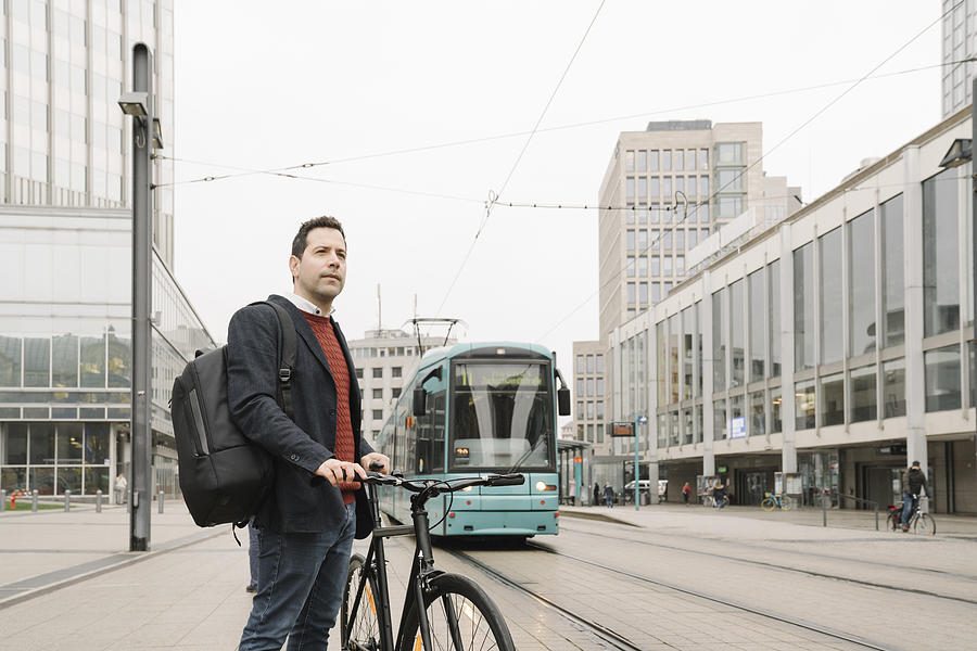 Entrepreneur with bicycle standing against cable car in city, Frankfurt, Germany Photograph by Westend61