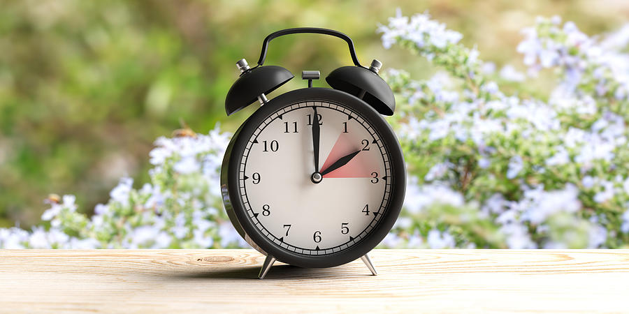 European daylight saving time. Alarm clock on wooden desk, blur spring nature background. 3d illustration Photograph by Rawf8