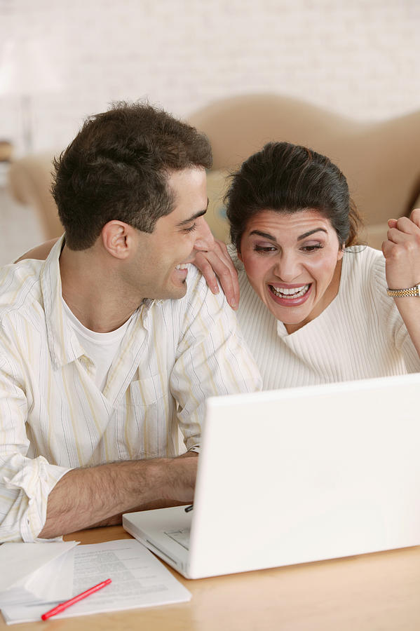 Excited woman using laptop at home Photograph by Comstock Images