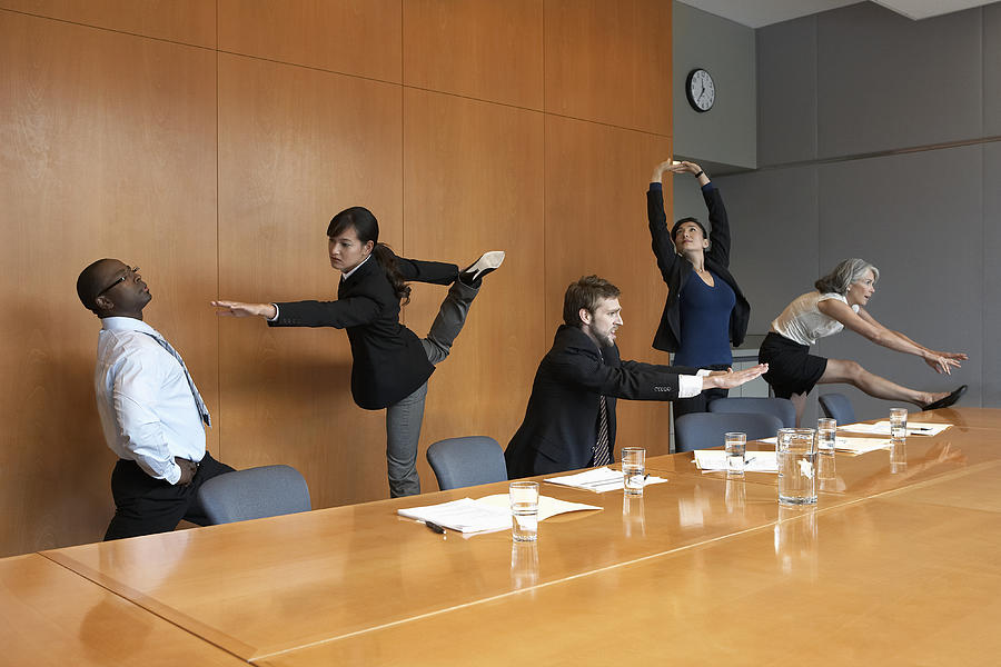 Executives in conference room stretching Photograph by Noel Hendrickson