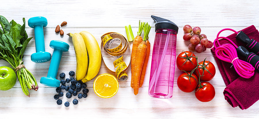 Exercising and healthy food: raibow colored fruits, vegetables and fitness items Photograph by Fcafotodigital