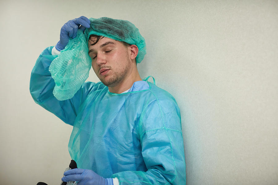 Exhausted Young Medical Worker Removing Protective Wear Photograph by Xavierarnau