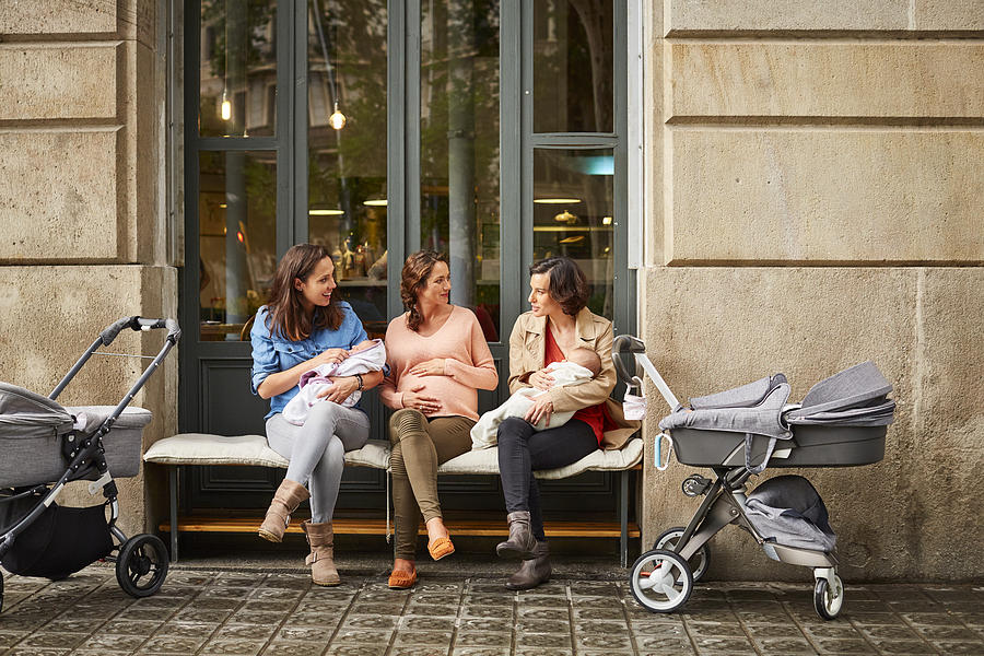 Expectant and friends with babies sitting on bench Photograph by Morsa Images