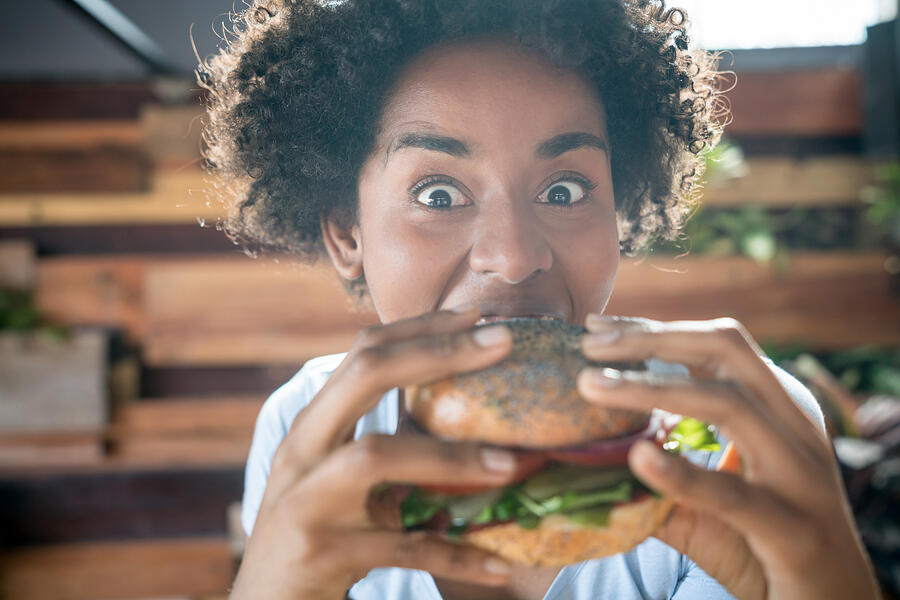 Expressive african american woman eating a delicious vegan burger Photograph by Andresr