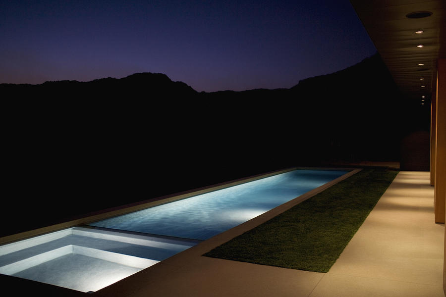 Exterior of modern house and swimming pool at night Photograph by Tom Merton