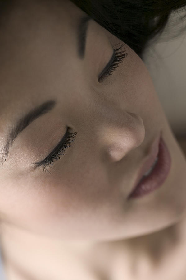 Extreme Close Up Shot Of A Young Adult Woman As She Lays Down And Closes Her Eyes Photograph by Photodisc