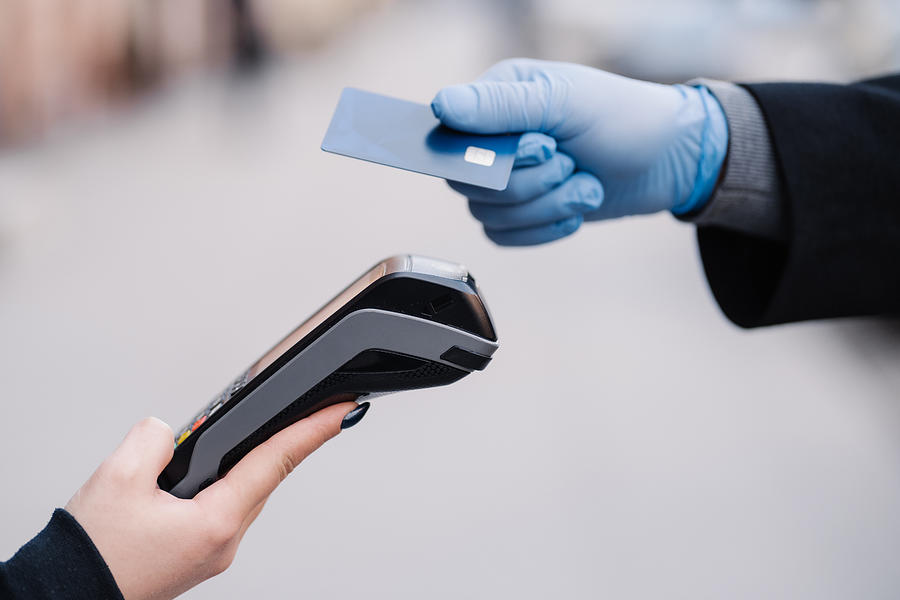 Faceless human in medical gloves during coronavirus epidemic, holds plastic card, tries to makes cashless payment for safety, uses modern technology. Pandemic, virus and prevention concept Photograph by Viorel Kurnosov