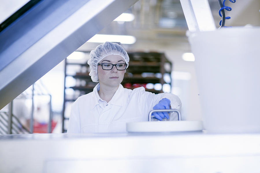 Factory worker wearing hair net in food production factory Photograph by Sigrid Gombert