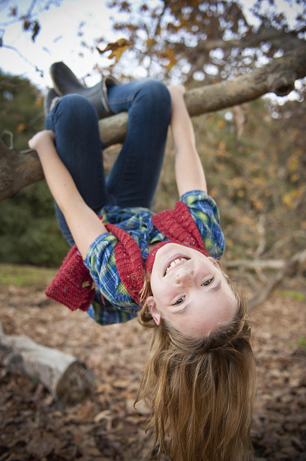 Fall, girl hanging upside down from tree branch Photograph by Stephen Simpson