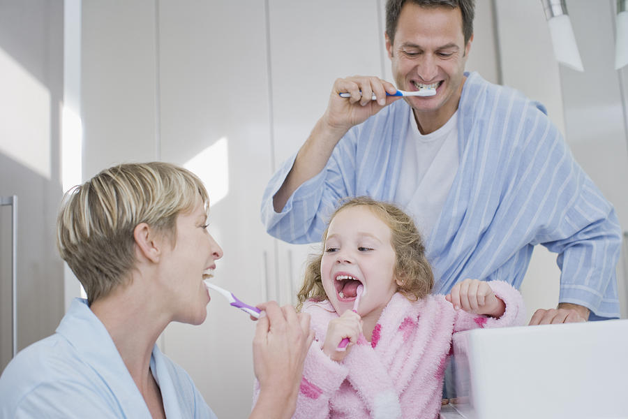 Family brushing teeth together Photograph by Sam Edwards
