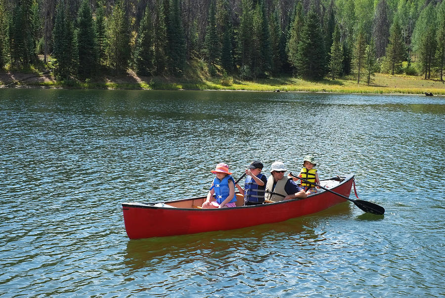 Family canoeing on lake in mountains Photograph by David Epperson