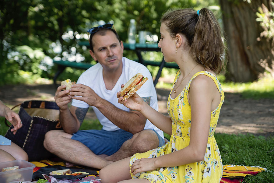 Family enjoying a picnic in public park in summer. Photograph by Martinedoucet