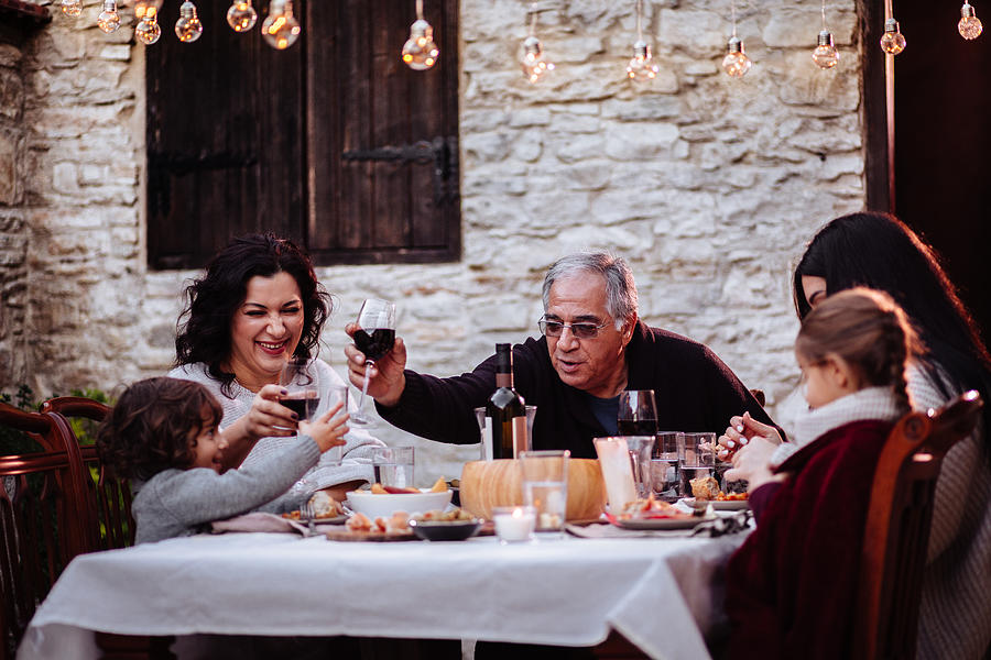 Family having fun and toasting with drinks at dining table Photograph by Wundervisuals