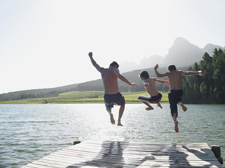 Family jumping into fijord Photograph by Image Source