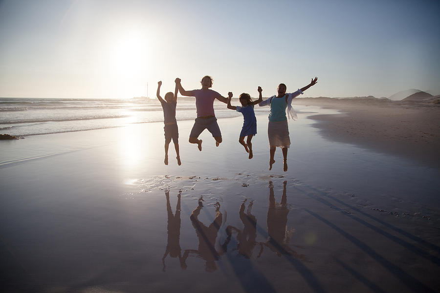 Family jumping together on a beach Photograph by Alistair Berg