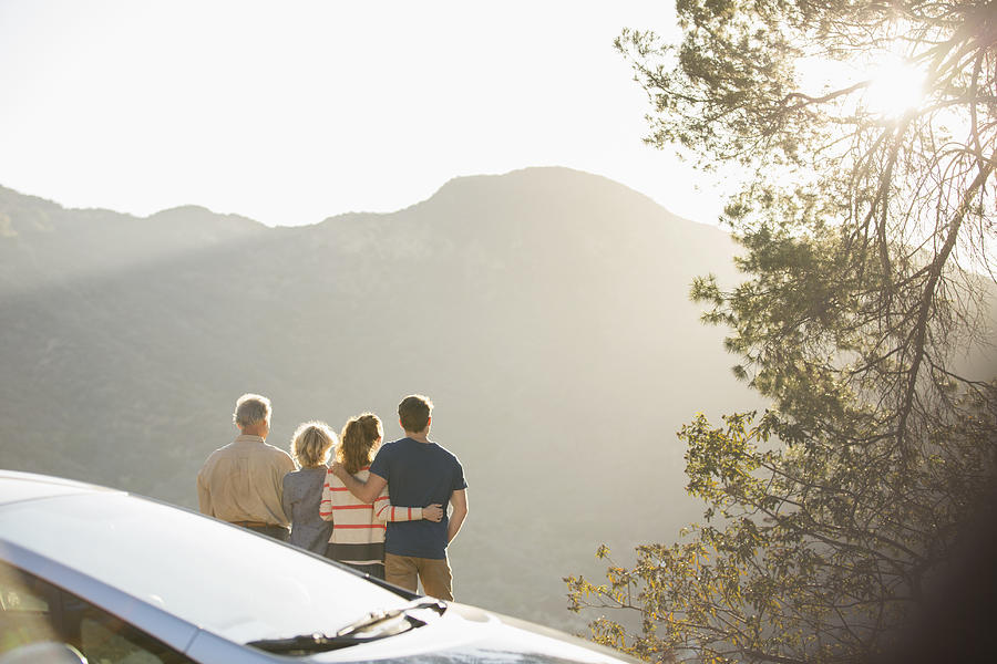 Family looking at mountain view outside car Photograph by Caia Image