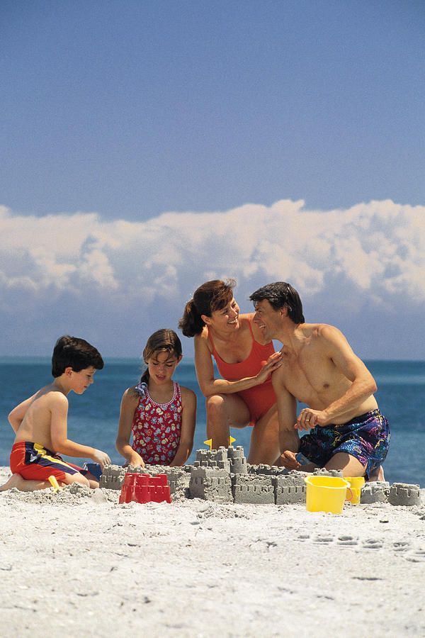 Family making sand castle on the beach Photograph by Comstock