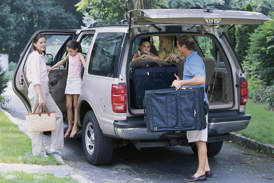 Family packing suitcases into SUV Photograph by Comstock