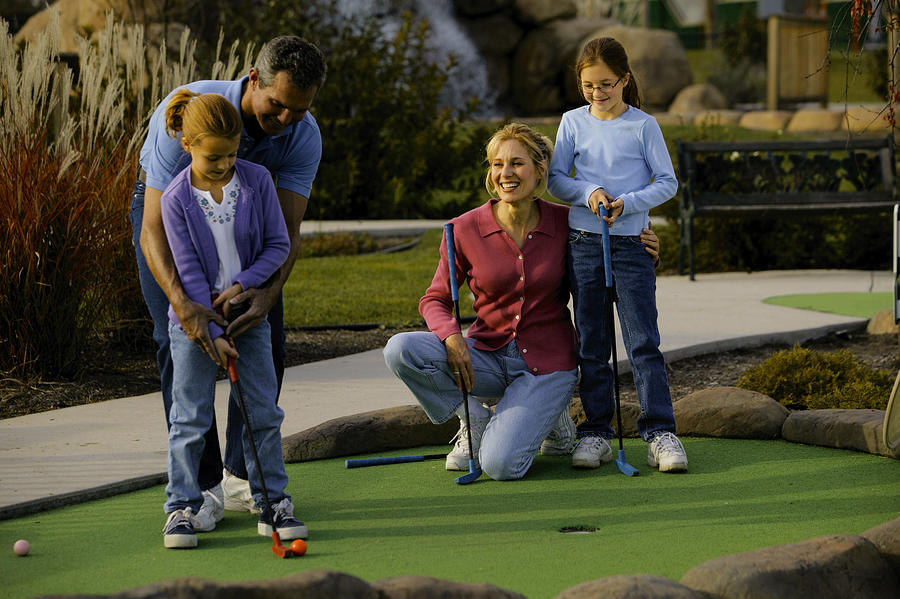 Family playing miniature golf Photograph by Comstock