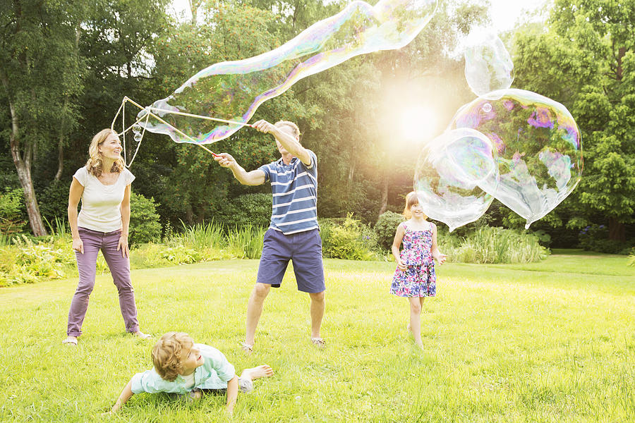 Family playing with large bubbles in backyard Photograph by Robert Daly