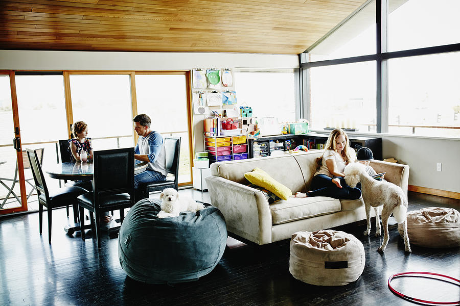 Family relaxing in living room of home Photograph by Thomas Barwick