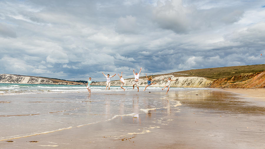 Family running and jumping along the beach Photograph by s0ulsurfing - Jason Swain
