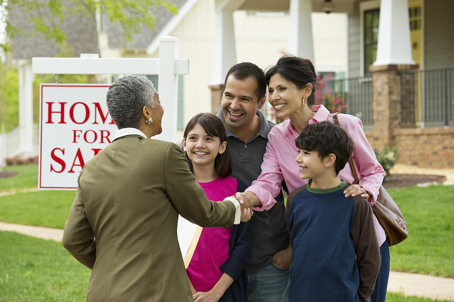 Family shaking hands with Real Estate Agent at new house Photograph by Ariel Skelley