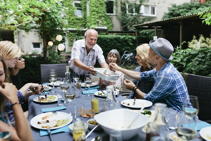 Family Sharing Food At BBQ In Courtyard Together Photograph by Hinterhaus Productions