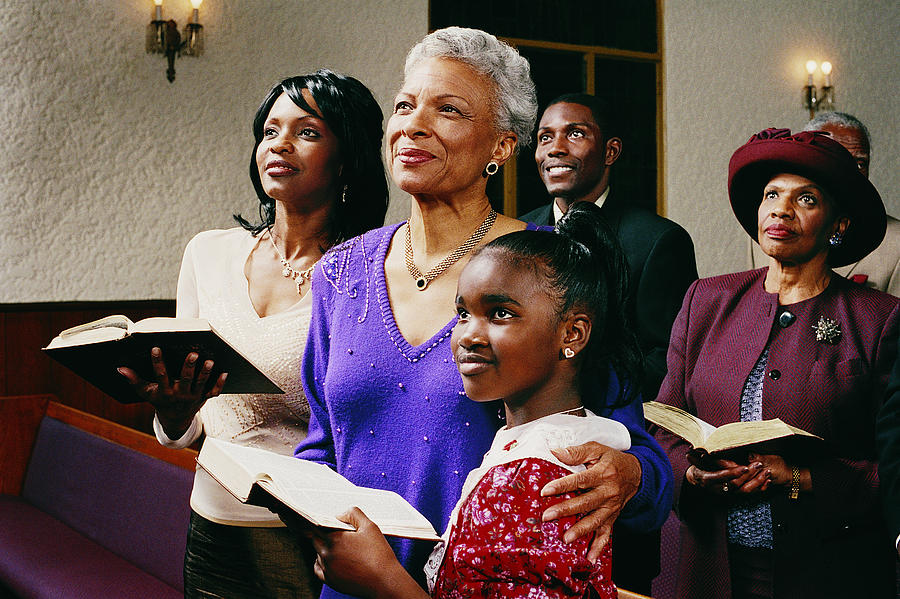 Family Standing in Church Pews Holding Bibles and Listening to a Service Photograph by Digital Vision.