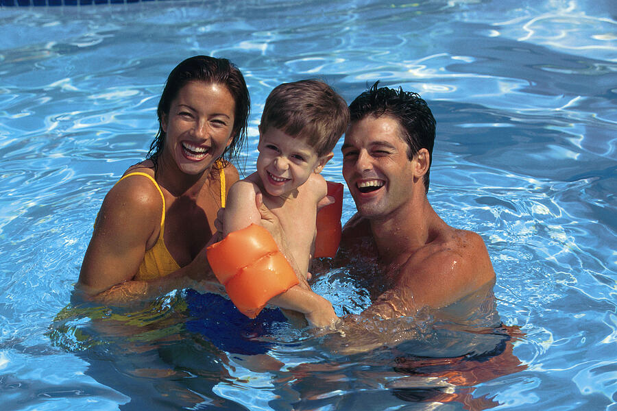 Family swimming in pool Photograph by Comstock