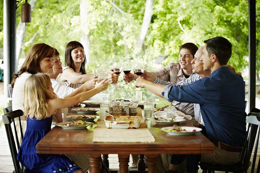 Family toasting at dinner table outdoors on porch Photograph by Thomas Barwick
