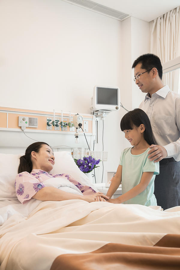 Family visiting the mother in the hospital, holding hands Photograph by XiXinXing