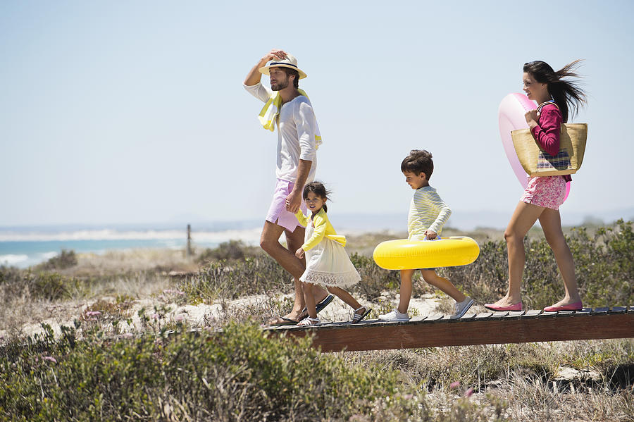 Family walking on a boardwalk on the beach Photograph by Eric Audras