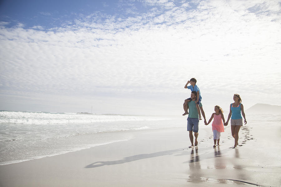 Family walking together on beach Photograph by Alistair Berg