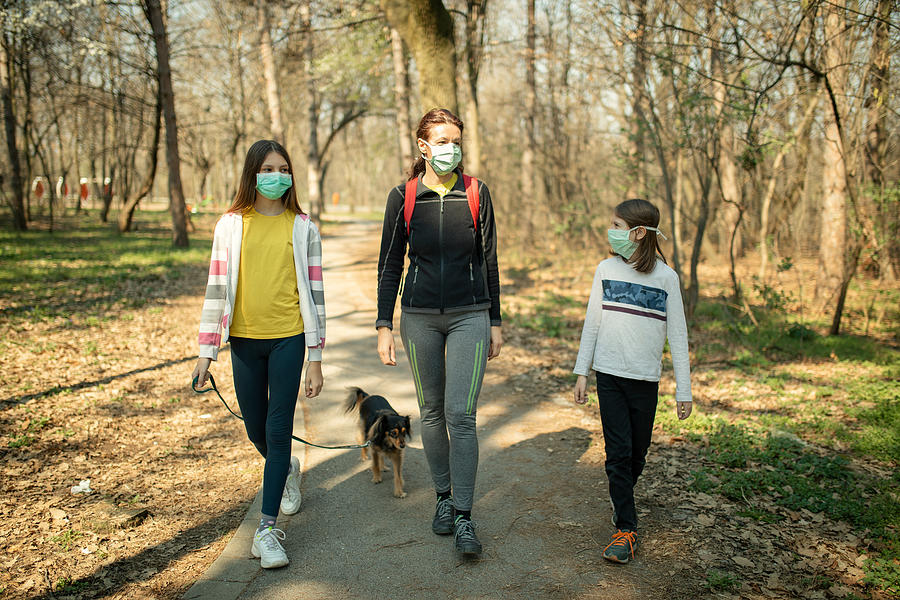 Family walking with their dog in park and wearing mask Photograph by Miljko