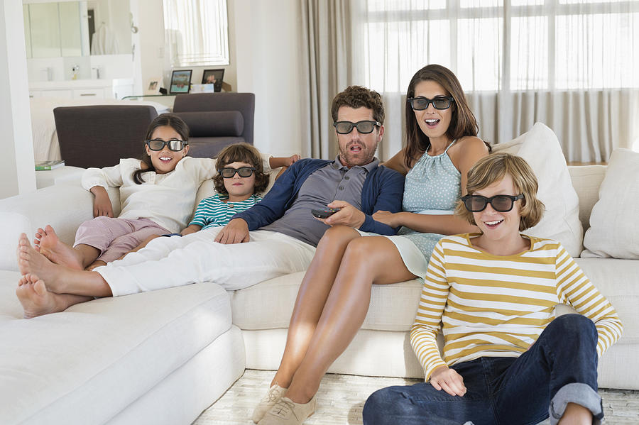 Family watching television at home while wearing 3D glasses Photograph by ONOKY - Eric Audras
