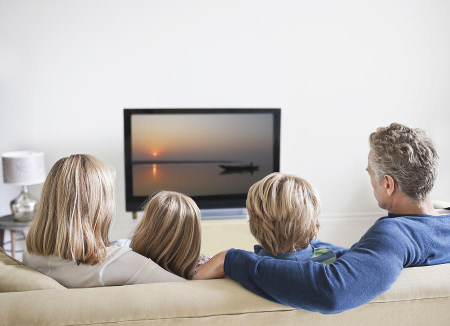 Family watching television, rear view Photograph by Compassionate Eye Foundation/Rob Daly/OJO Images Ltd