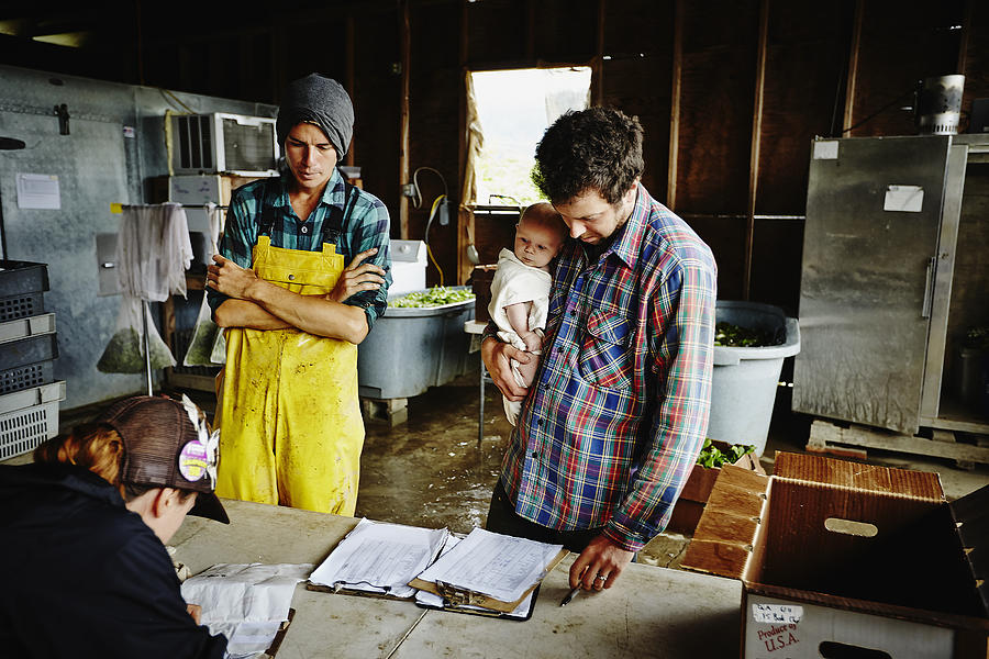 Farm owner holding infant looking over log Photograph by Thomas Barwick