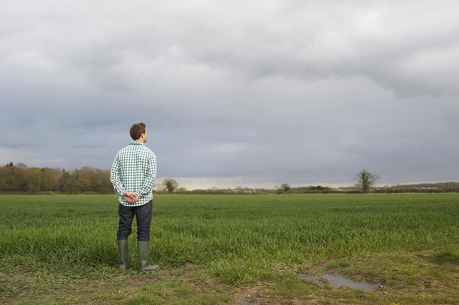 Farmer at edge of field looking across land. Photograph by Dougal Waters
