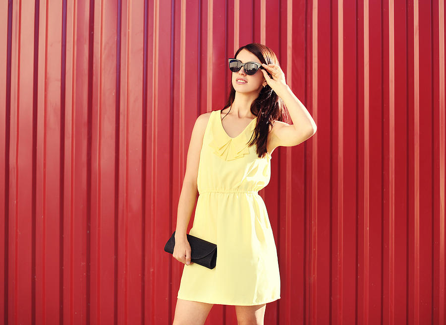 Fashion woman wearing yellow dress and sunglasses with handbag clutch Photograph by Rohappy