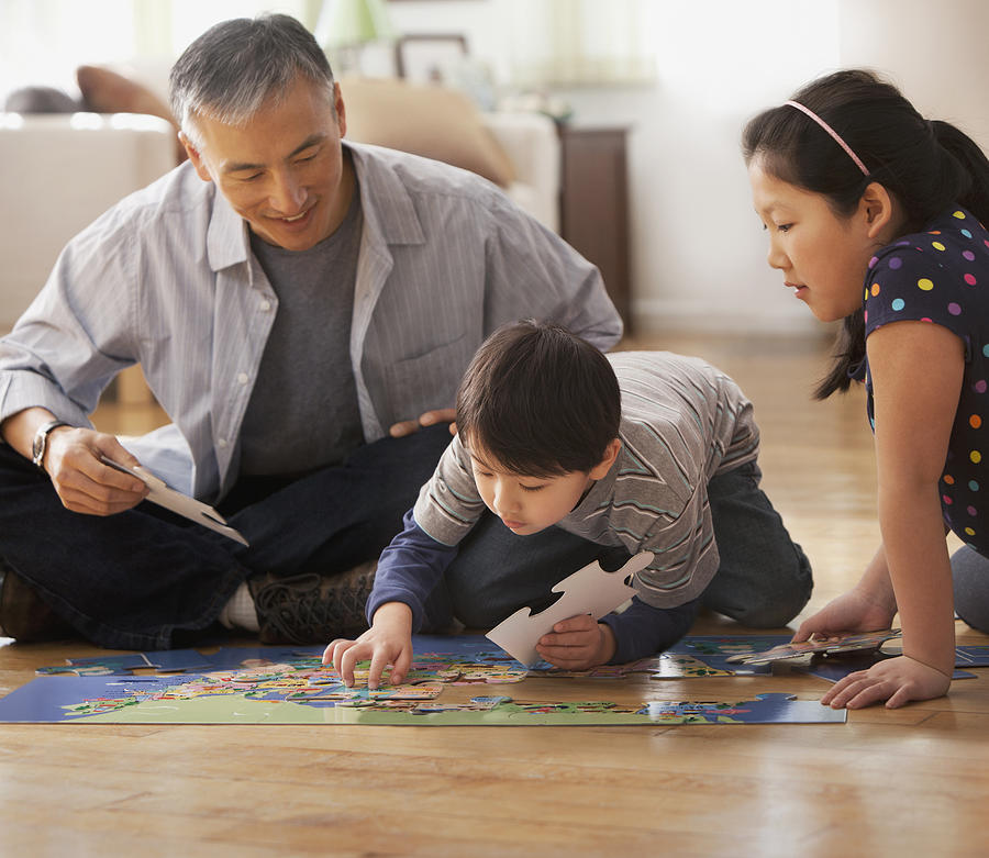 Father and children doing jigsaw puzzle together Photograph by Jose Luis Pelaez Inc
